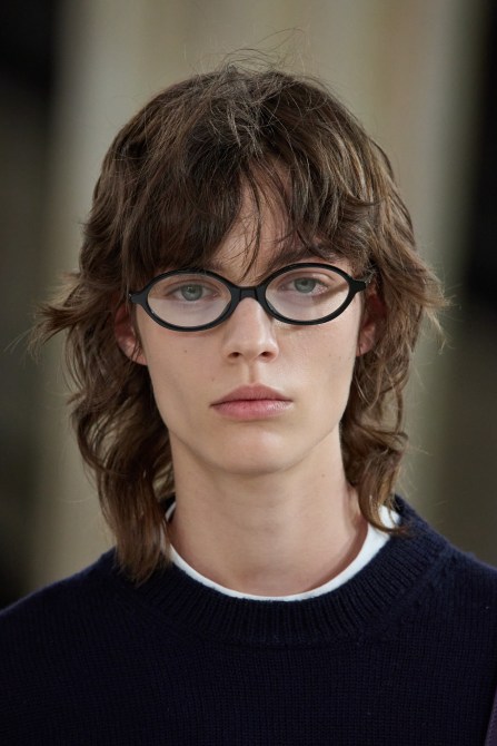 Runway model wearing round black glasses.