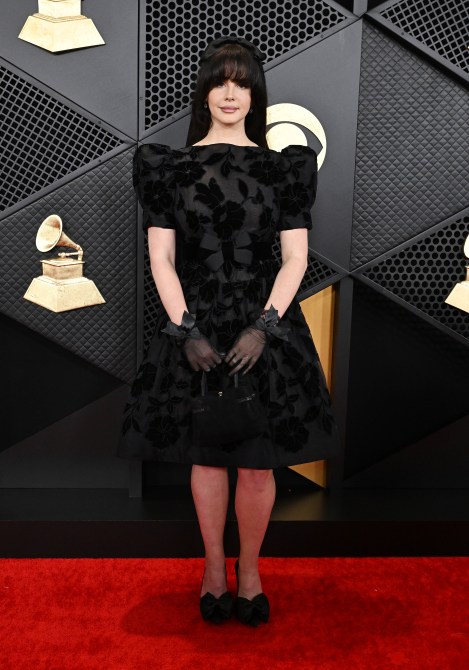 Lana Del Rey at the 66th Annual GRAMMY Awards in a black velvet dress, black gloves, and black hair bow