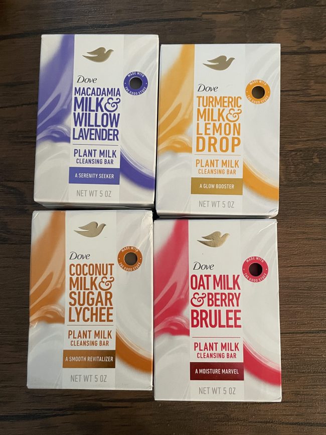 Four boxes of Dove Plant Milk Cleansing Bars laid next to each other on a wooden background