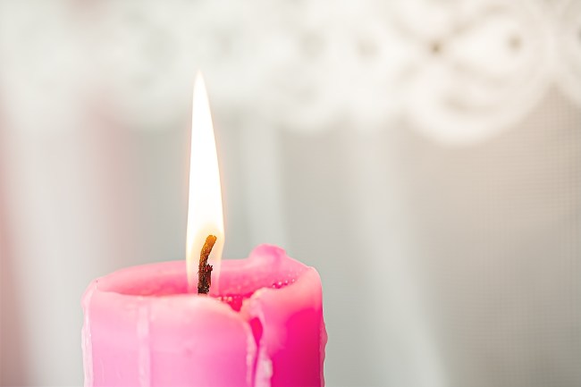 Pink candle with burning flame during a love spell or healing spell