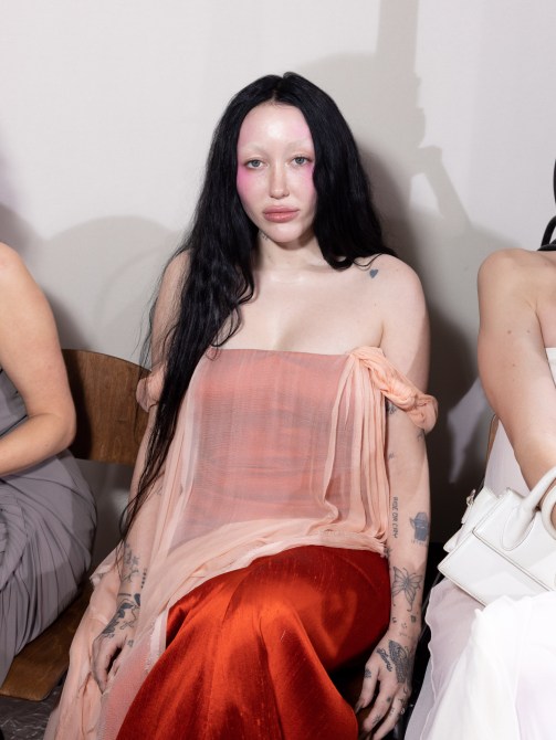 Noah Cyrus with long black hair and bleached brows.