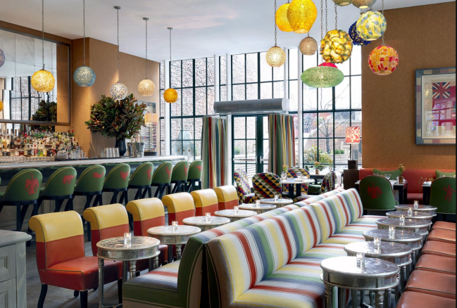 The dining area at The Crosby Street Hotel, which features colorful chairs, pendant lamps, and barstools