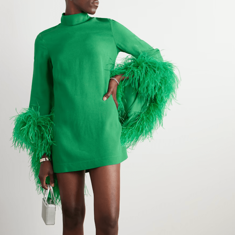 A model wearing a high-neck, feather-sleeve green mini dress