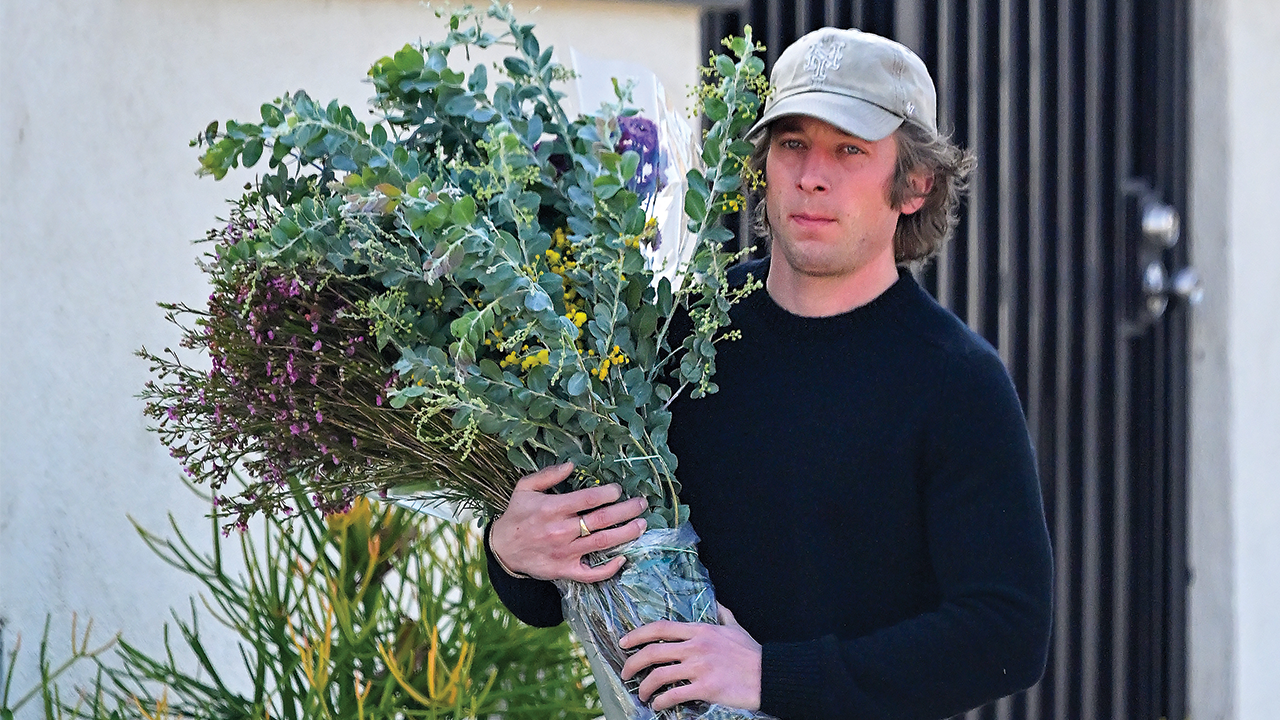Jeremy Allen White carrying a large bouquet of flowers.