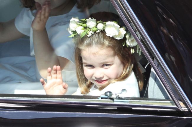 Princess Charlotte waves to the crowd as she rides in a car to the wedding of Prince Harry and Meghan Markle at St George's Chapel in Windsor Castle on May 19, 2018 in Windsor, England.