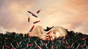 Kim Petras for her Viva Glam campaign in a pile of lipsticks with a sunset behind.