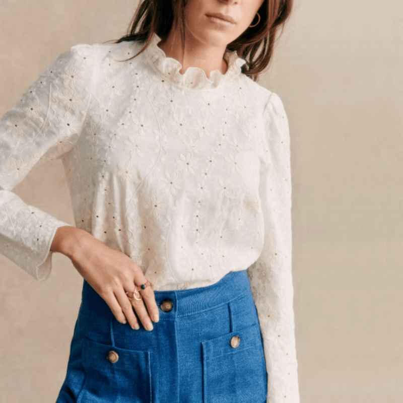 White Sézane blouse with floral embroidery and a ruffle collar. 