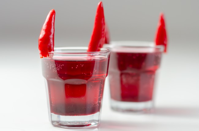 Drink shot prepared with vodka, grenadine and lemon juice decorated with bird eye chillies in the shape of horns