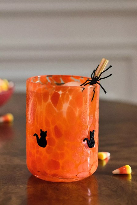 An orange cup with black cats on it