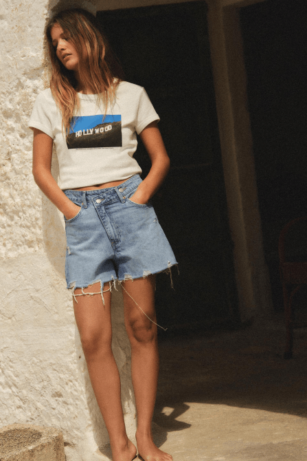 A model wearing the Zara High Rise Cross Waist Mom Fit TRF Denim Shorts